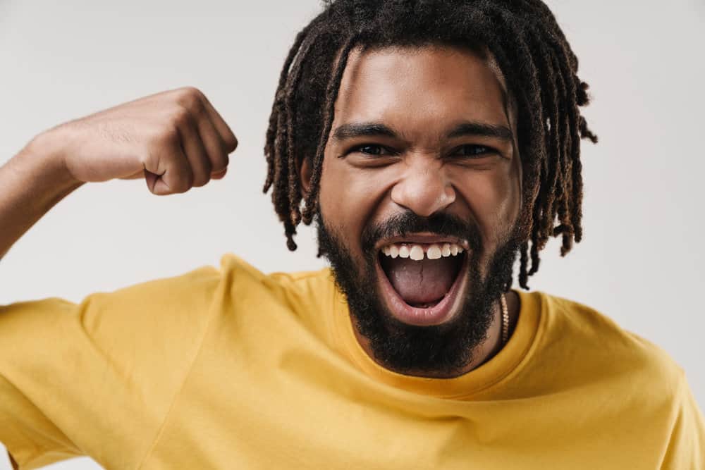 A happy young black man lets his hair breathe while allowing his locs to grow organically.