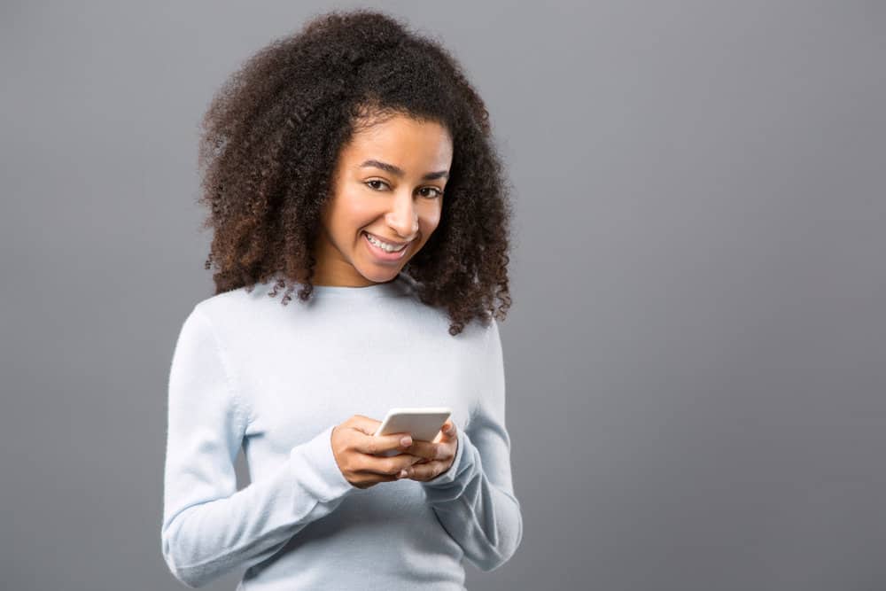 A joyful young female researching how an injured area heals while using her iPhone 14 mobile device.