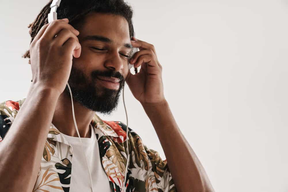 A man listening to music on Beats headphones wearing thick locs that have been freshened with the re-twist method.