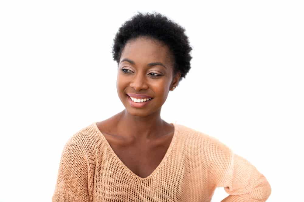A black female with low hair porosity uses leave-in conditioners to retain moisture on her tightly coiled strands.