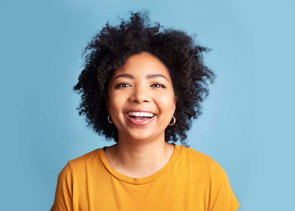 An attractive woman with should length hair growth uses Curly Girl hair styling products like aloe vera gel.