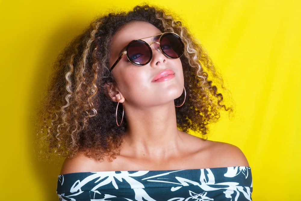 A black lady with curly new growth wearing a darker hair color with red undertones.