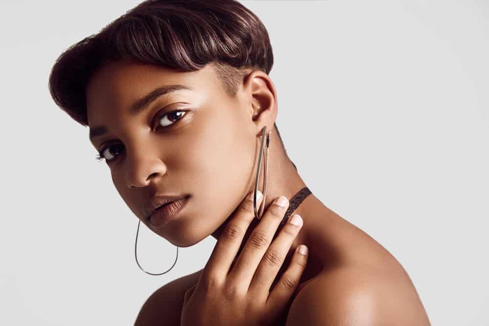 A young female with a cool skin tone wearing silver hoop earrings and a black lace choker necklace.