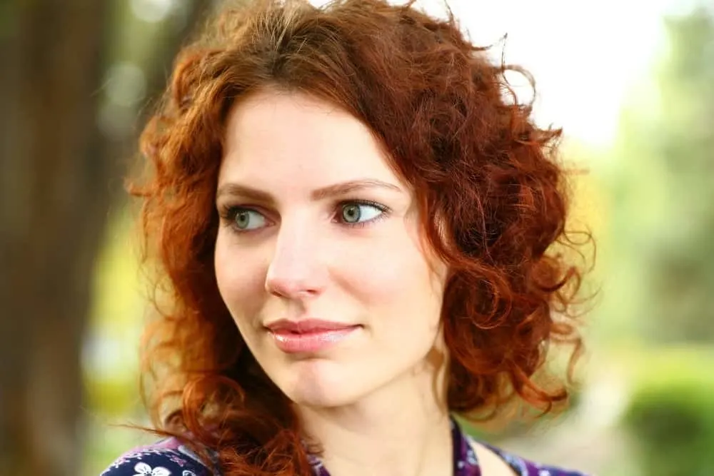 A redheaded female with an S-shaped enhanced curl pattern in medium texture defined ringlets.