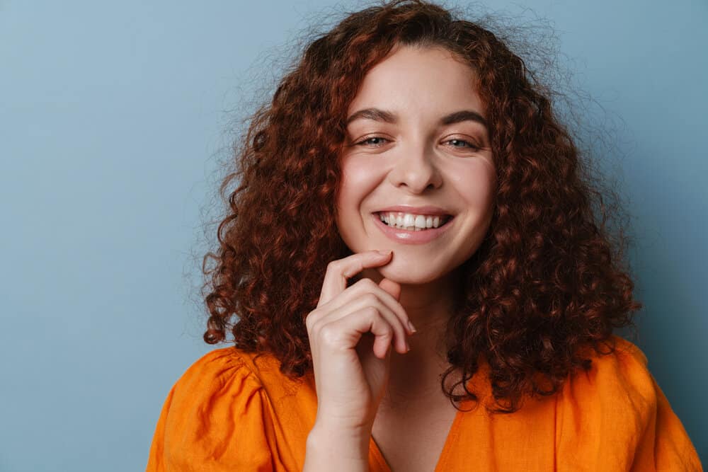 A cute redheaded female with a great smile has her curls styled with waving lotion and a good deep conditioner.