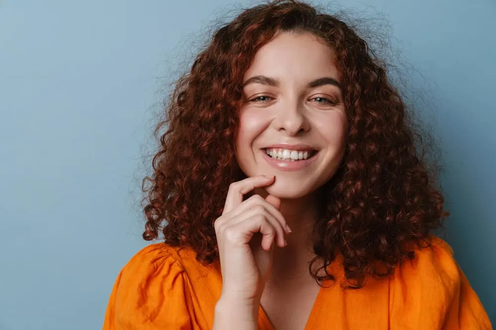 Get a Perm Out: How to Unperm Your Hair Naturally at Home 7 A cute redheaded female with a great smile has her curls styled with waving lotion and a good deep conditioner.