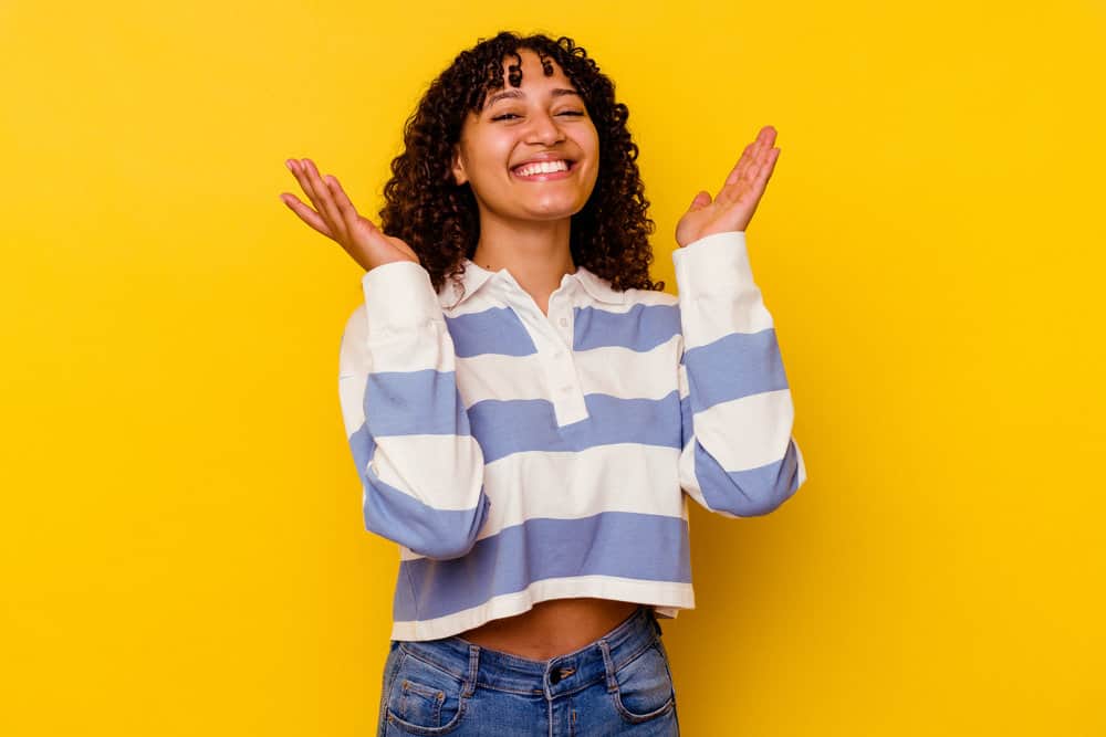 A joyful black female with a great smile with naturally curly hair styled with hair products designed to fight head lice.