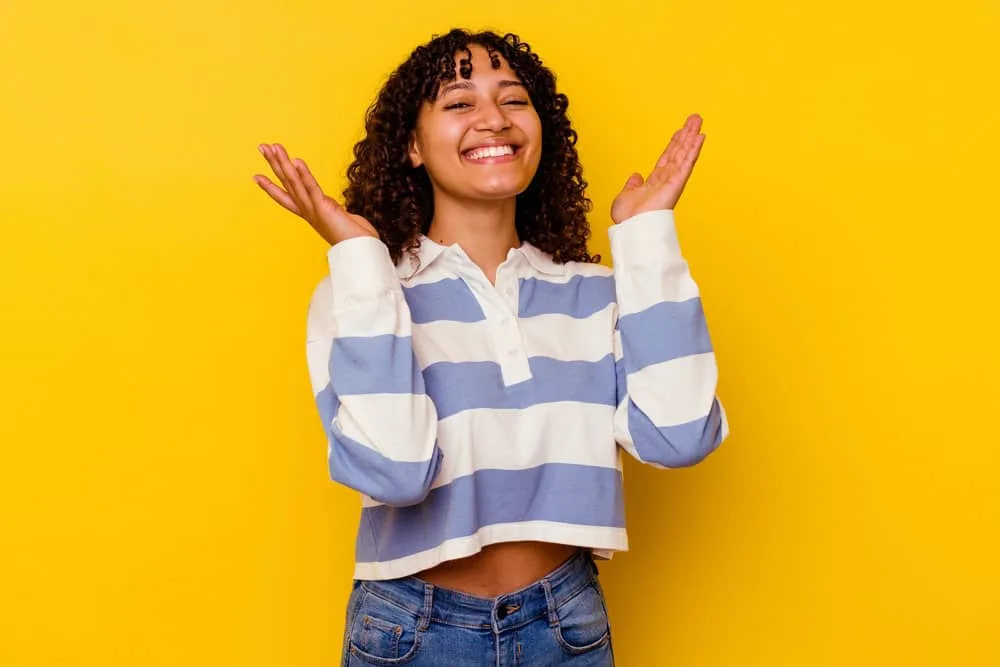 Does Your Scalp Itch When Your Hair Is Growing? Solutions? 7 A joyful black female with a great smile with naturally curly hair styled with hair products designed to fight head lice.