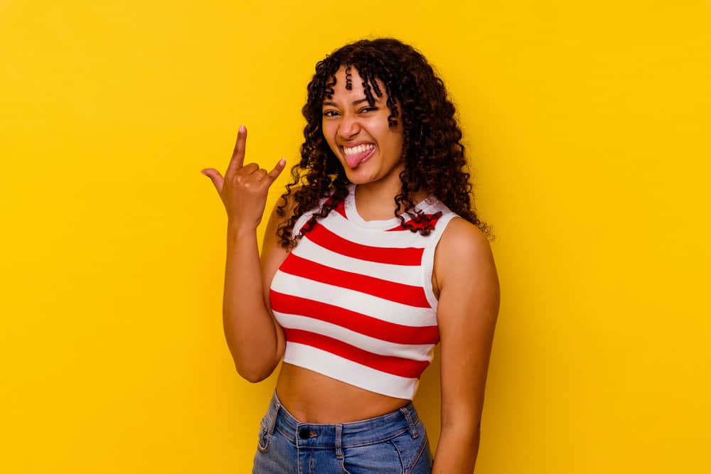 A young black lady with kinky, curly hair strands wearing loose curls in a wash-n-go style that's perfect for coily hair.