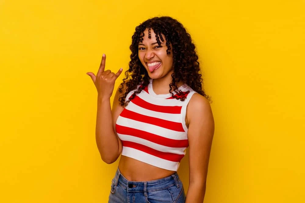 Curly vs. Kinky Hair: Difference Between Curly and Kinky Hair 1 A young black lady with kinky, curly hair strands wearing loose curls in a wash-n-go style that's perfect for coily hair.