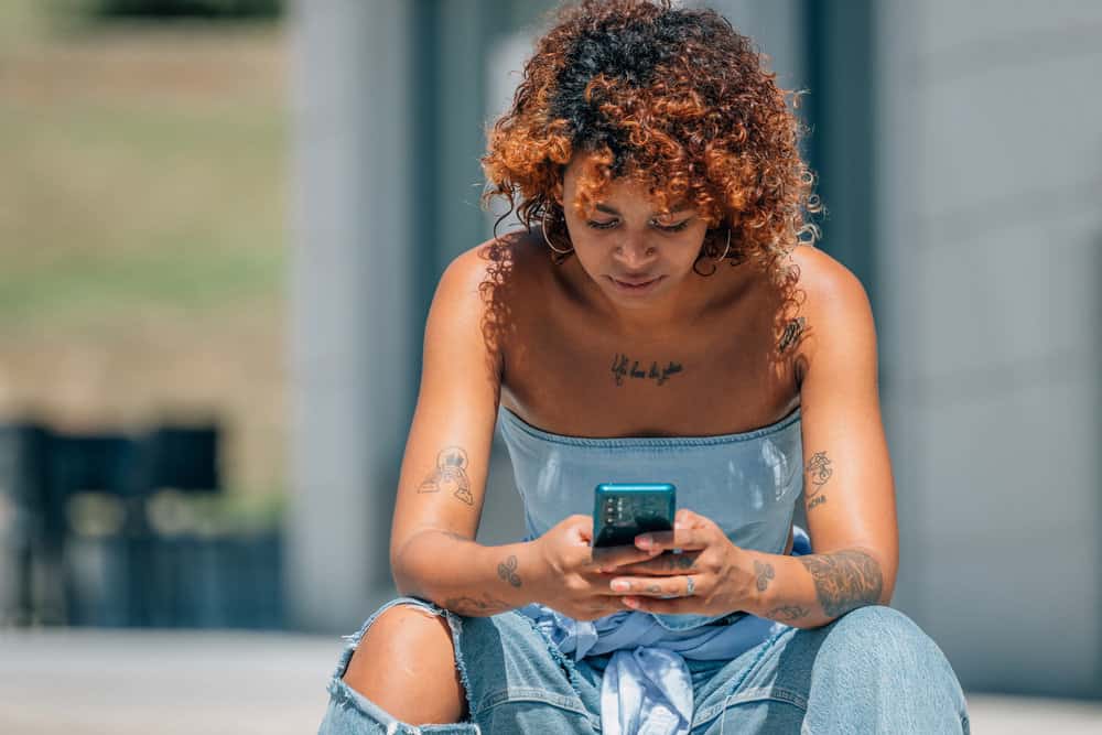 An urban Latin African American female researching whether you can dye bleached hair with store-bought box dye.