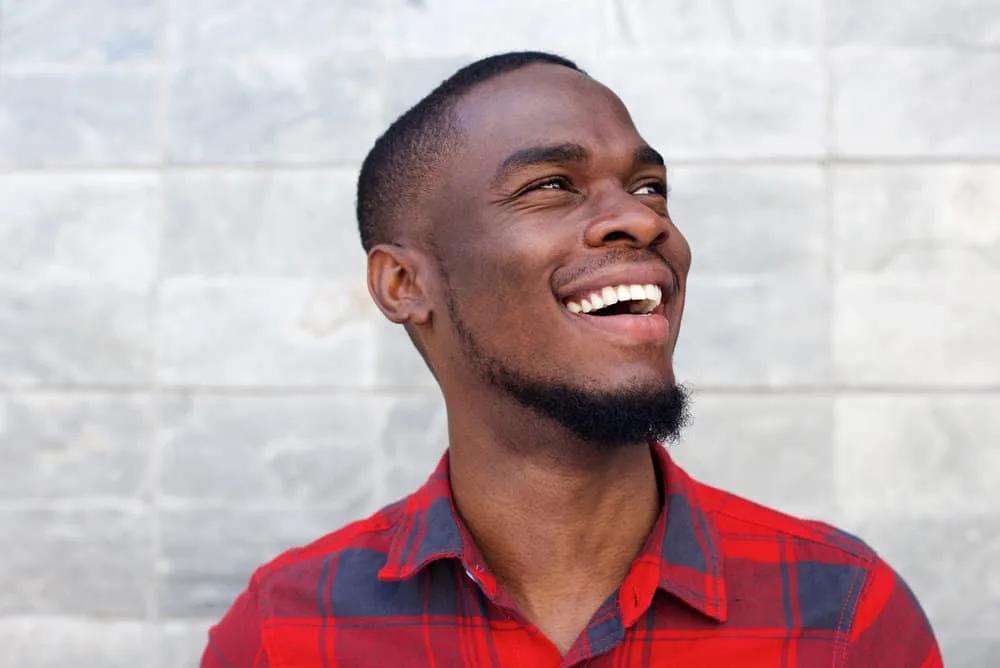 28 Different Types of Fades and Tapered Haircuts for Men 4 A young black wearing a low-skin fade haircut with a type 4 hair texture while sporting a plaid casual dress shirt.