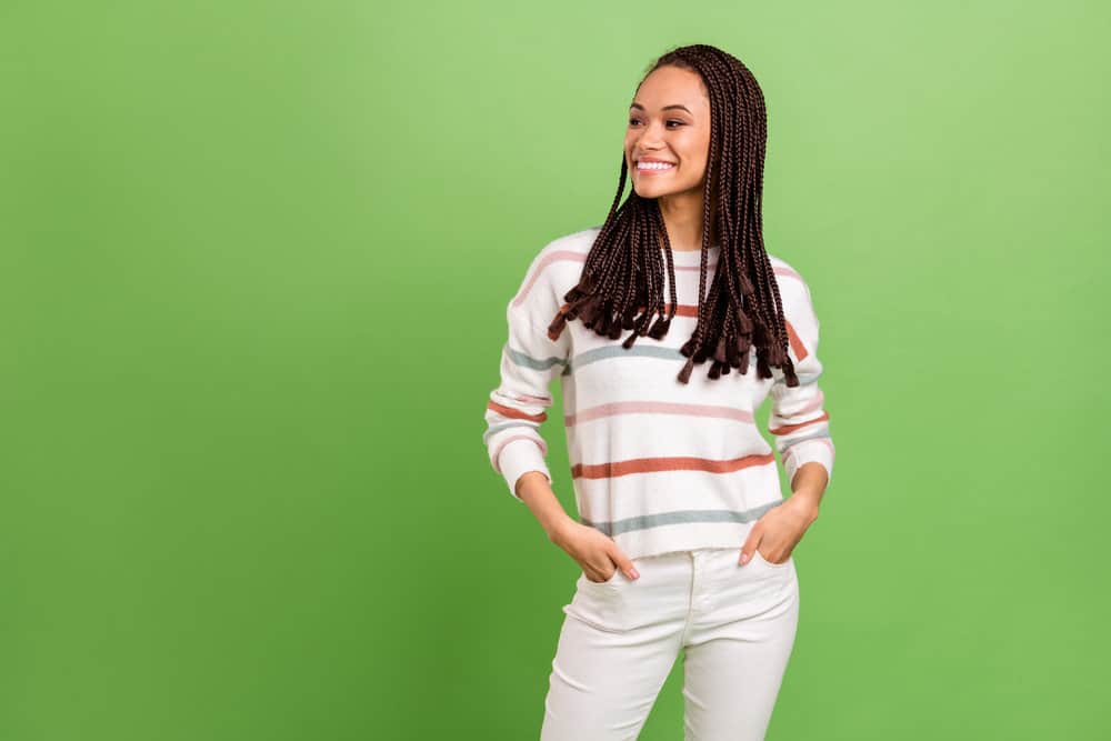 A dreamy black female used heat styling tools to create straight hair as she prepared her natural hair for braids.