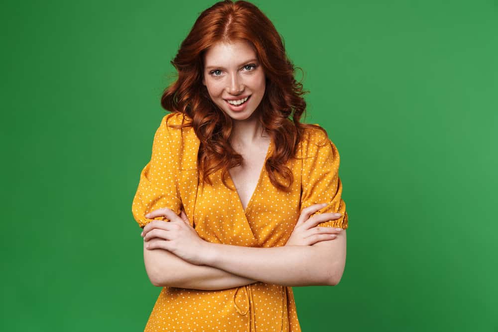 A white lady with natural 2A hair strands treated with lemon juice to lighten her hair, highlighting her red streaks.