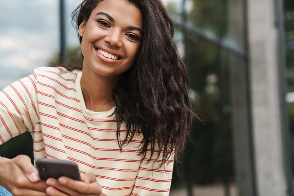 A black woman wearing a flat iron hairstyle after using a heat protectant on her naturally wavy texture.