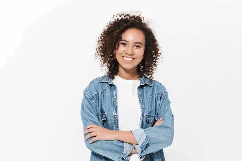 How to Get Rid of Layers in Hair: DIY Step-by-Step Guide 6 A cheerful black woman that knows it's just a matter of time before she has split ends with her damaged layered cut.