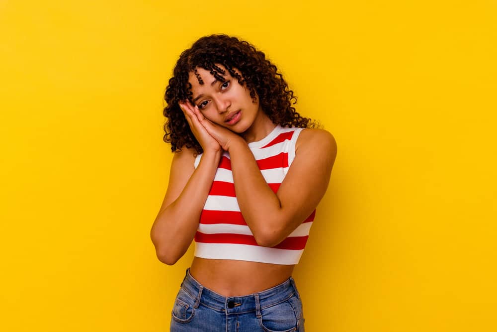 A light-skinned African female with curly natural hair experienced hair breakage coming from color-treated hair.