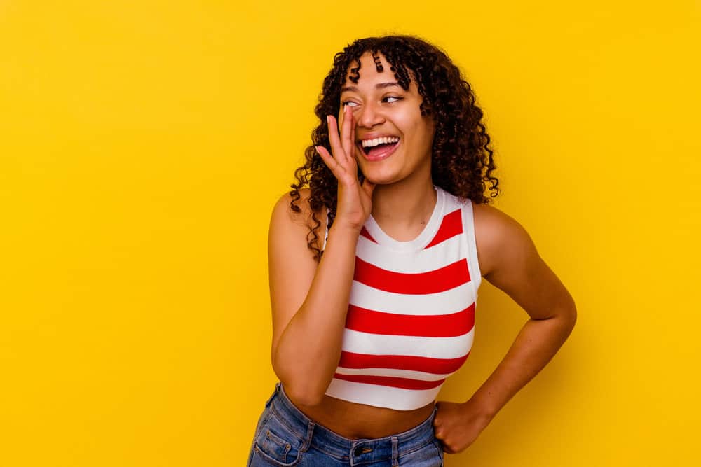 A black woman with a curly perm has thicker hair that's styled with hair products designed for relaxed hair.