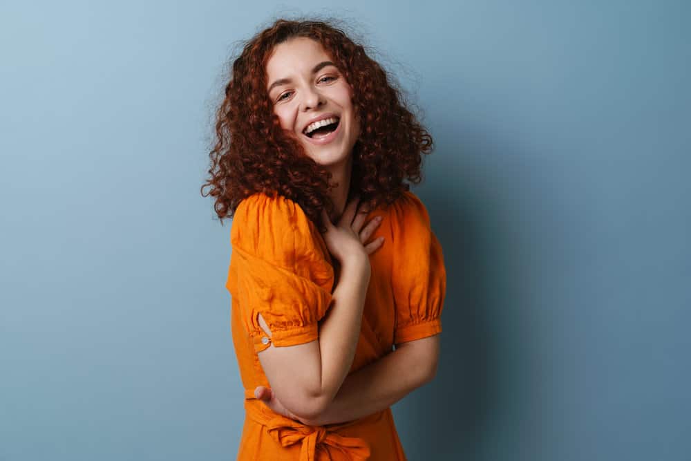 A cheerful redhead with red natural hair washed with a sulfate-free shampoo and moisturized with coconut oil.