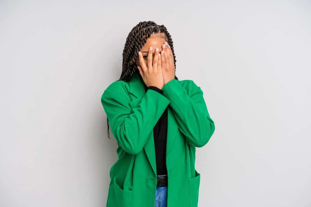 Does Twisting Your Hair Make It Grow Faster and Longer? 5 A black lady covering her face wearing tight twists in a style that looks like box braids more so than other hairstyles.