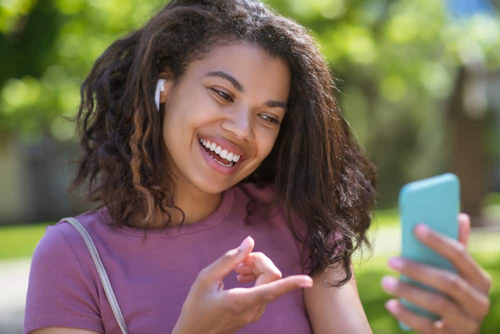 A cute young black girl researching how hair absorbs water and various wet hair conditions on her iPhone.