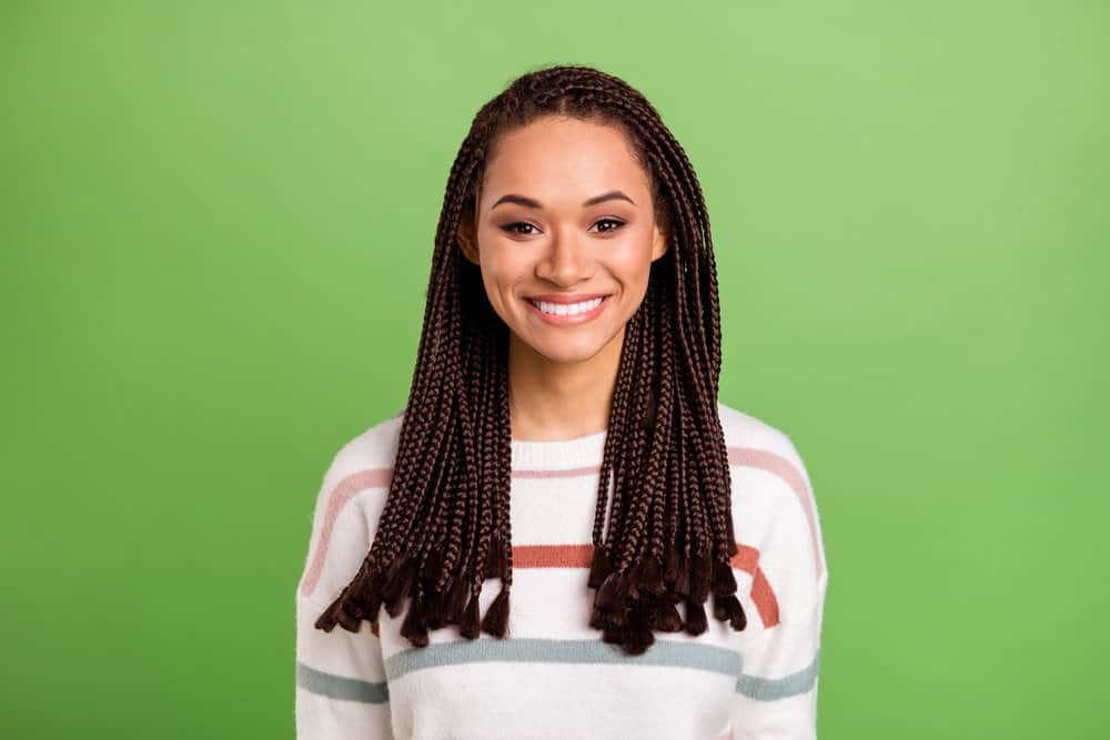 Black female with fresh braids after making her synthetic hair soft using a wide-tooth comb and lukewarm water.