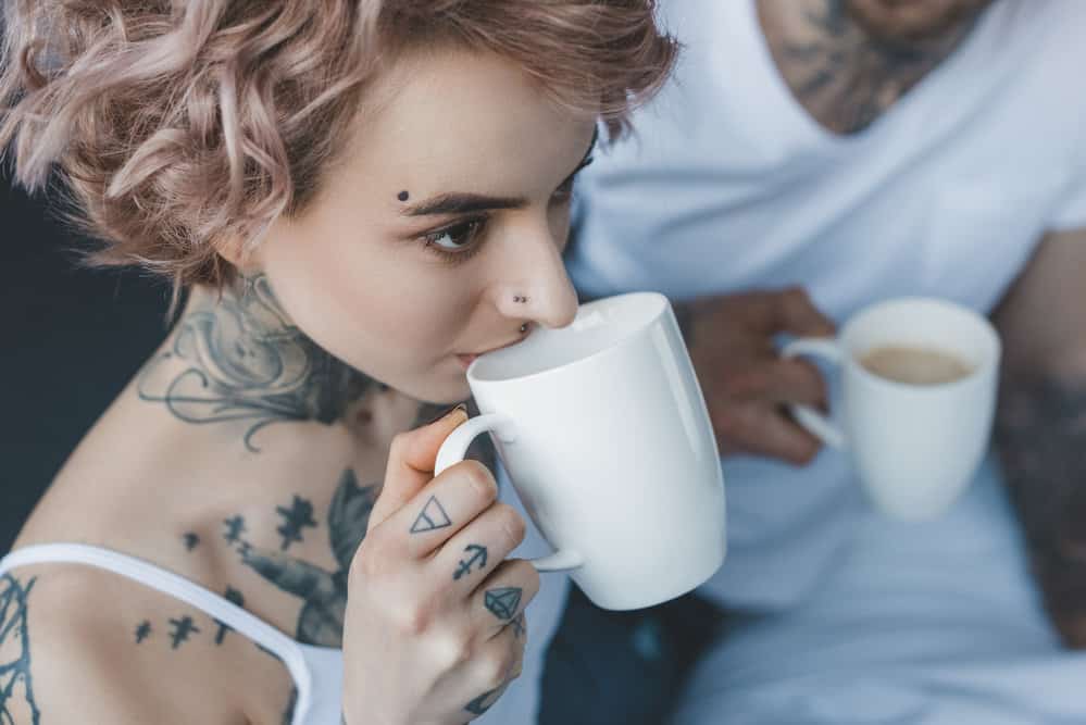 Two tattoo artists sitting in the shop early one-morning drinking coffee and discussing the best tattoo process.