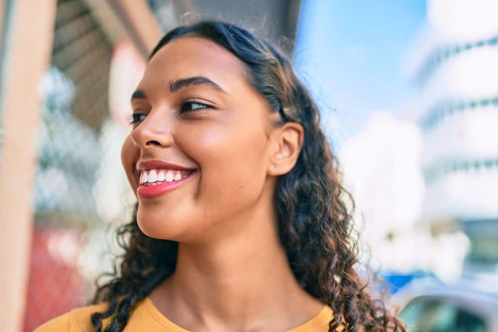 A cute black woman with healthy hair growth around her previously thinning hair edges styled with castor oil.