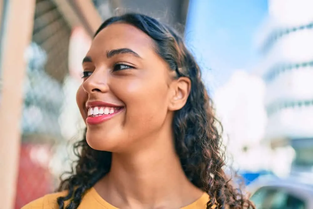 How Long Does It Take for Edges to Grow Back? Bald Edges? 2 A cute black woman with healthy hair growth around her previously thinning hair edges styled with castor oil.