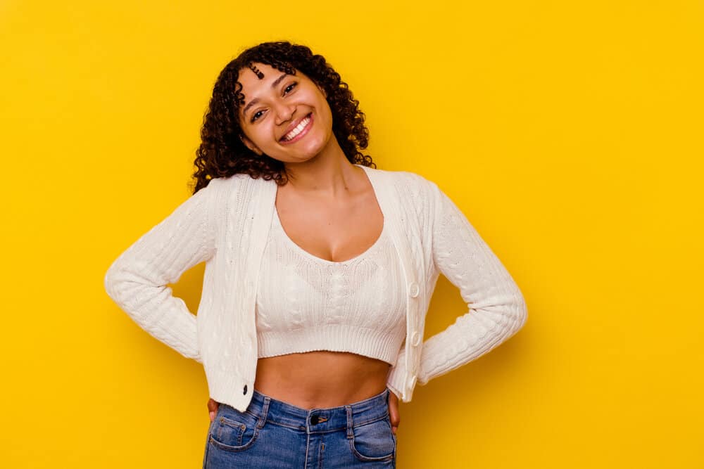 A young mixed-race female with loose curls and 3B hair texture is wearing a hair texturizer to achieve frizz-free curls.