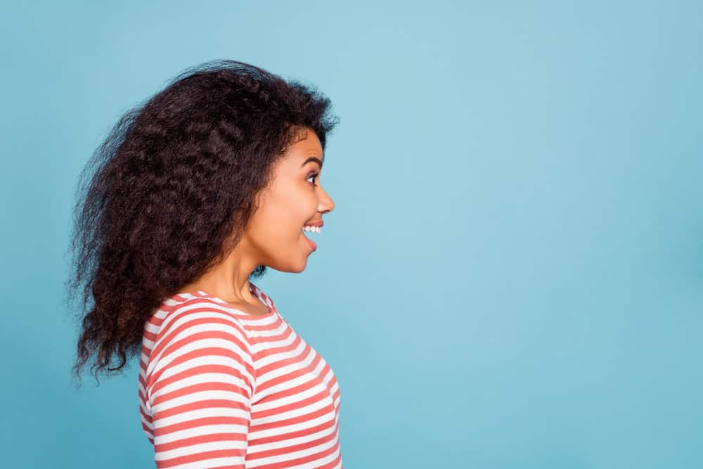 A charming black woman with thick hair recently got a trim haircut to remove choppy layers and frayed ends.