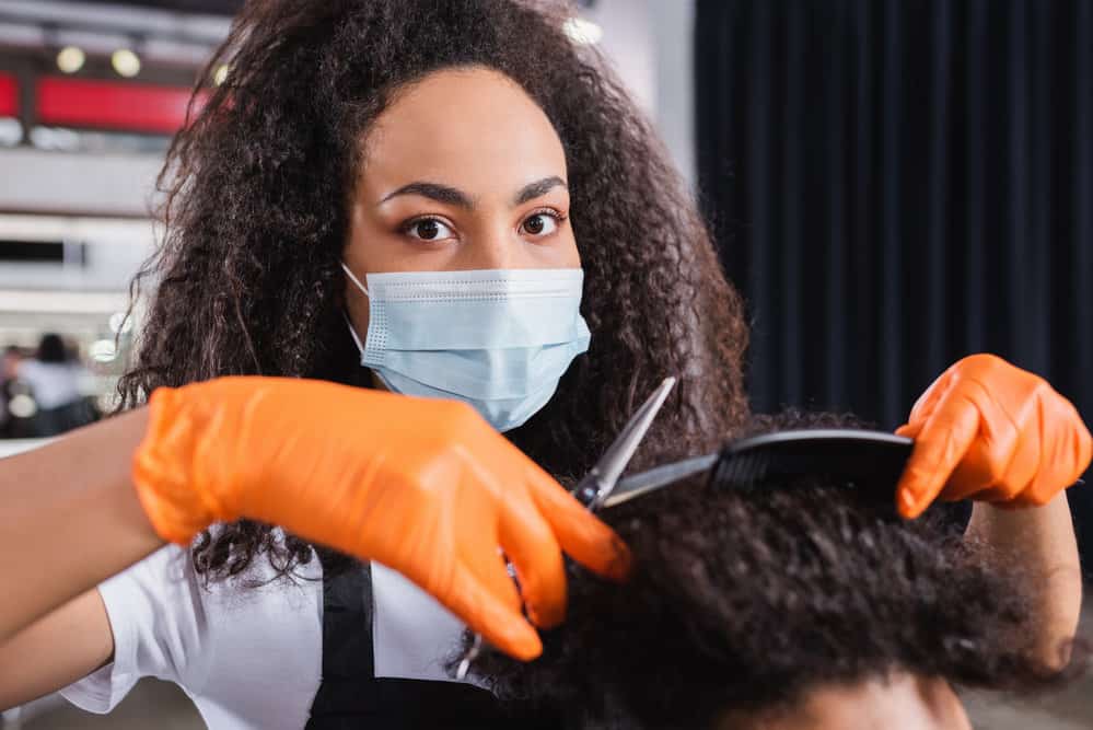 A black hairstylist provides shampoo, a blow dry, and a full haircut service at a hair salon in Birmingham, Alabama.