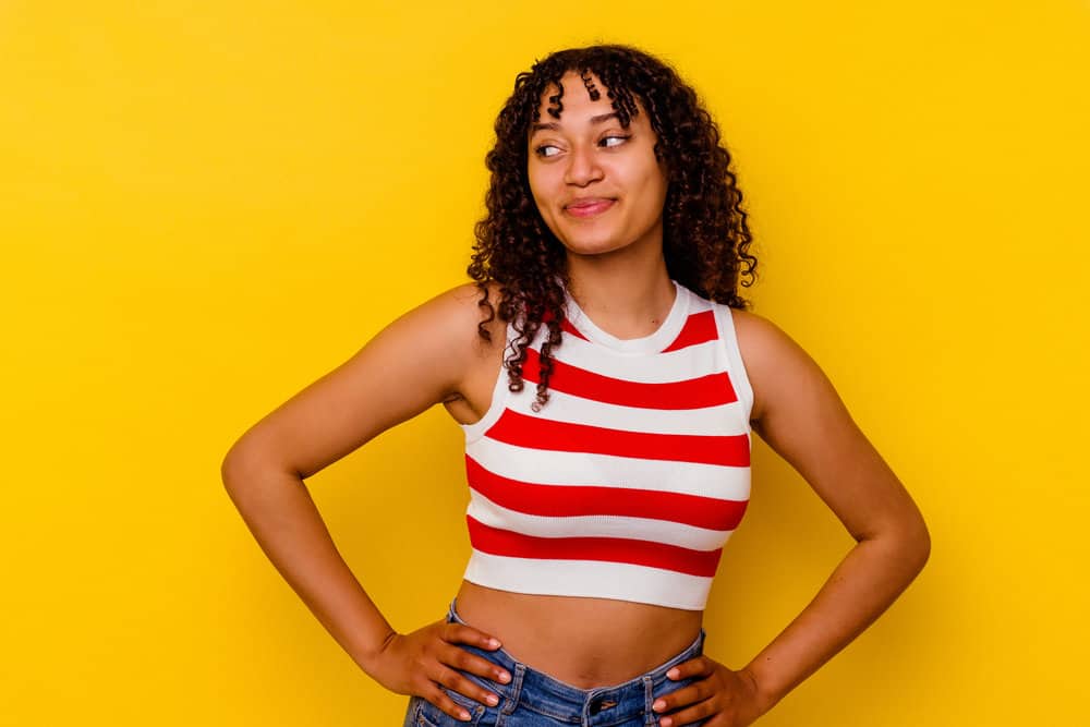 A lady wearing a red and white half-sweater used Curly Girl-approved hair products on her natural 3B curls.