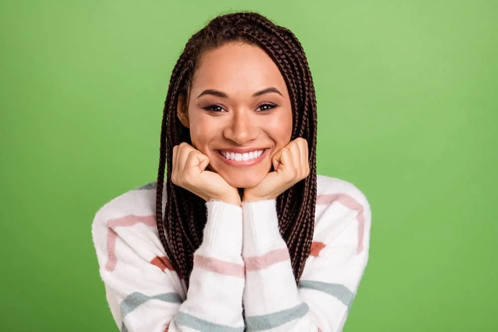How To Soften Synthetic Braids: Step-by-Step for Beginners 1 A cheerful young female with synthetic hair extensions combined with her real hair moisturized with coconut oil.