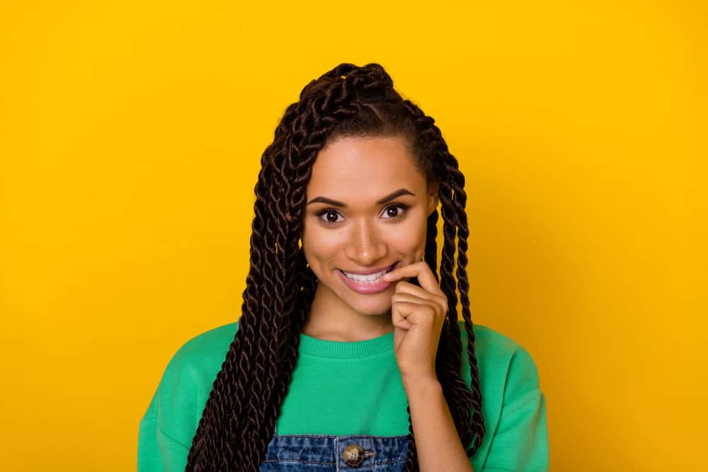 A cute black woman with healthy hair wearing in 2C waves in a braided protective hairstyle to encourage hair growth.