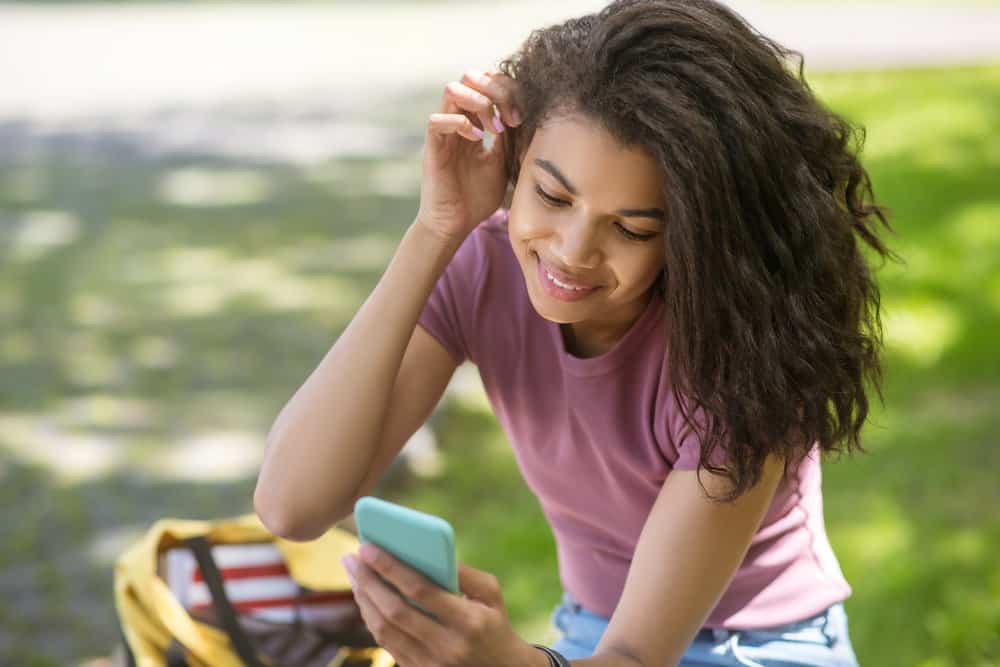 A cute African American female with light brown skin reading about how to maintain good moisture resistance.