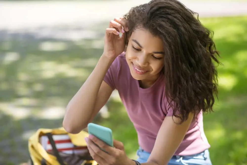 Flash Drying Hair: Is It Bad, Causes, How to Fix It, and More 5 A cute African American female with light brown skin reading about how to maintain good moisture resistance.