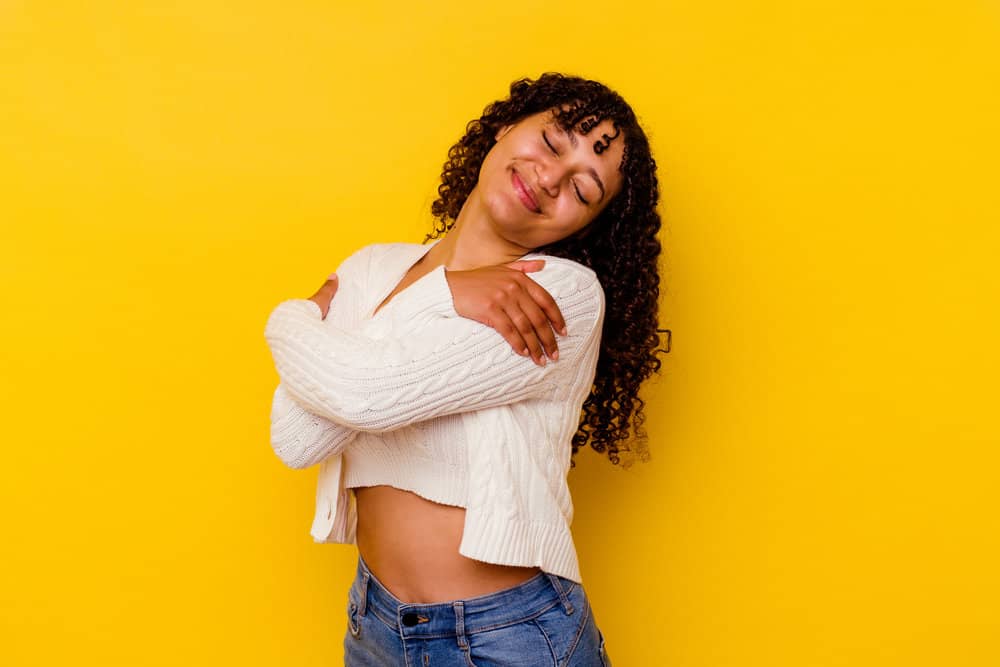 A black girl showing off her curly hair after implementing hair care tips while using a neutralizing shampoo.