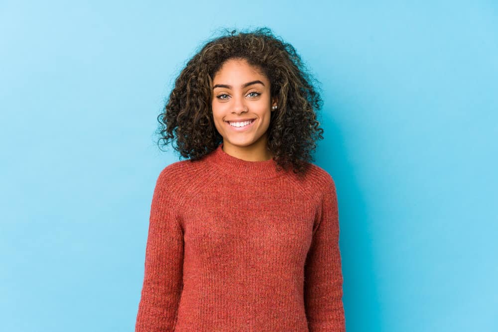 A young African American female with dry hair uses a cleansing conditioner routine to make her frizzy hair soft.