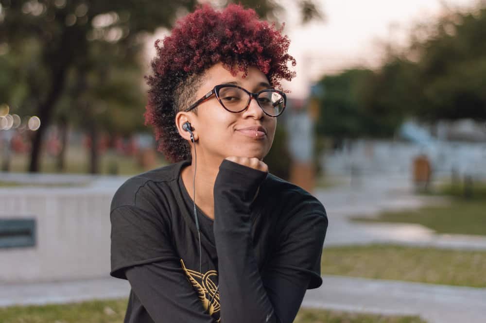 A Latin woman with a sensitive scalp and curly hair follicles after bleaching her hair for a red hair dyeing session.