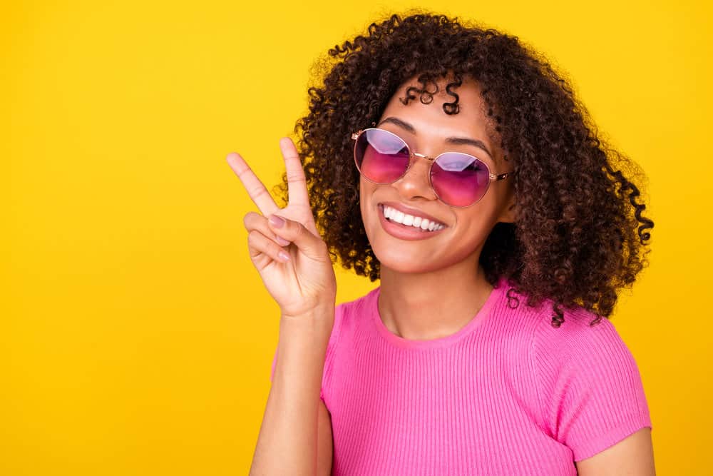 A black lady with a frizzy 3C hair type has curly hair styled with lightweight products designed for her natural texture.