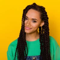 Adorable female with curly and coily hair strands in box braids used a heat protectant before her hair braiding session.