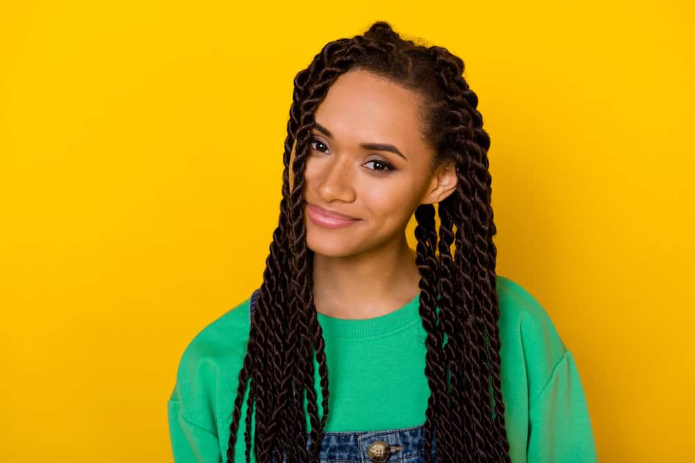 Adorable female with curly and coily hair strands in box braids used a heat protectant before her hair braiding session.