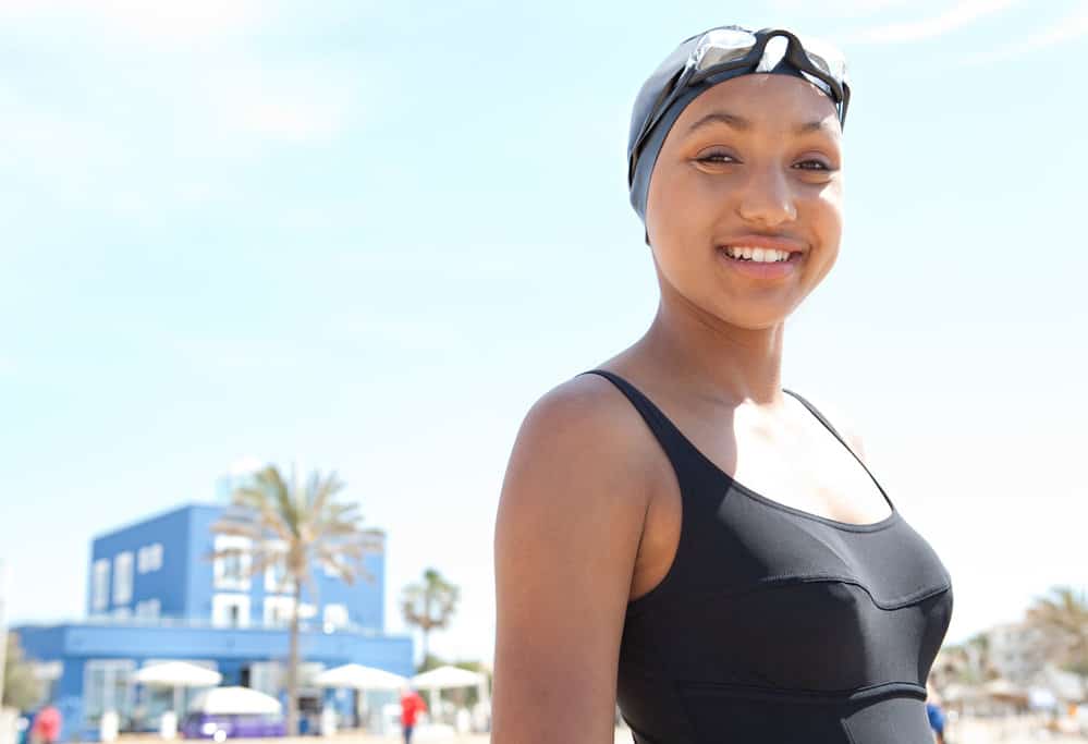 A light-skinned young lady that styled her hair with natural oils is wearing a lycra cap to keep her hair completely dry.