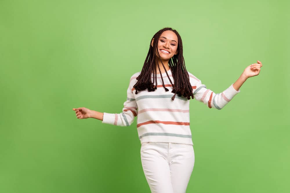 A nice dark skin female wearing braids where the hair extension tips are loose like tiny wavy craft tassels.