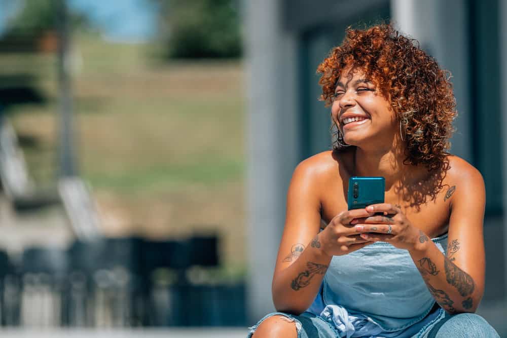 A light-skinned black lady researching if she can dye hair with semi-permanent hair color to test her desired shade.