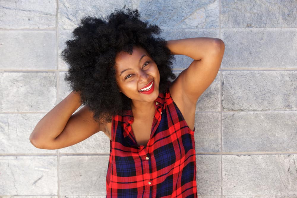 A beautiful black woman with curly hair bends gently around her oval face, styled with styling creams for 4A curls.