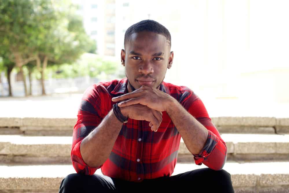 Young African American man with naturally type 4 curly locks wearing a high skin fade haircut