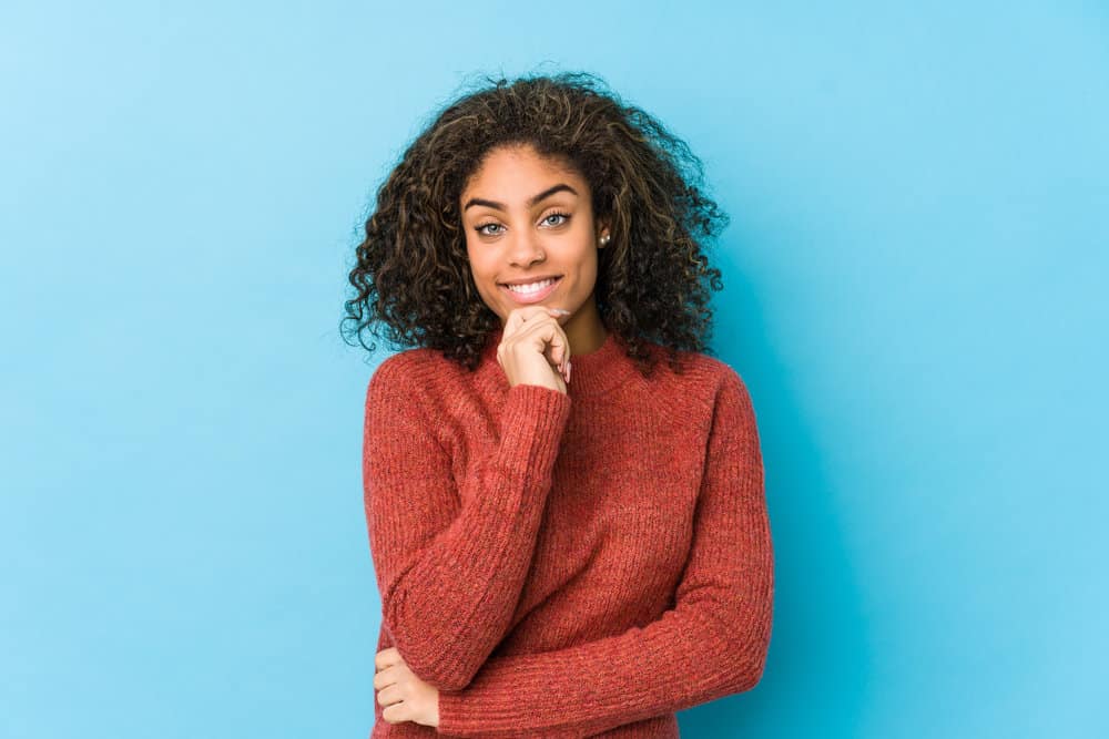 A young black female with shiny coarse hair has split ends and used conditioner to repair the hair's cuticle.