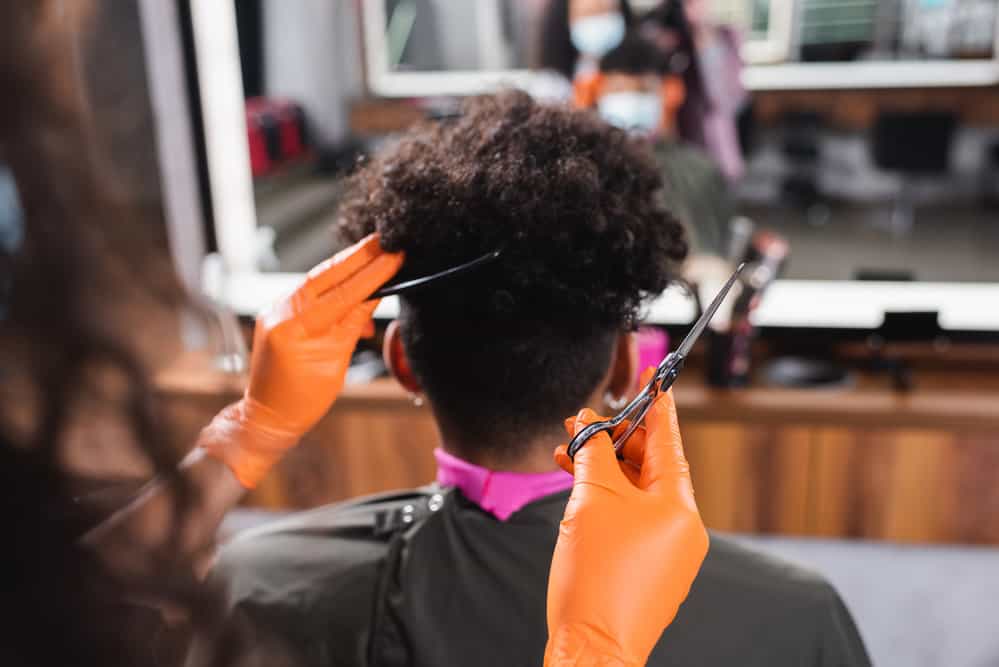 A black man gets a haircut where women pay the same amount as men, and cuts are based on the stylist's time.